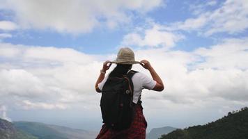 Backpacking female hiker stands on top of the mountain and enjoying the view. journey and success concept video