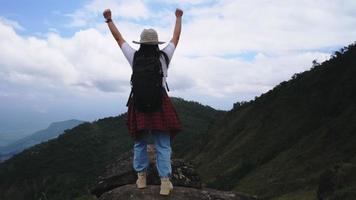 una excursionista mochilera se encuentra en la cima de la montaña y disfruta de la vista. concepto de viaje y éxito video