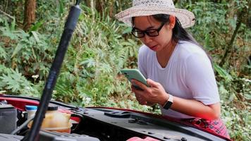 Stressed female driver uses her smartphone and social media to seek help from car assistance services as her car breaks down in the woods. video