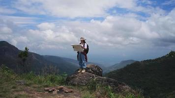 femme hipster avec sac à dos en regardant une carte sur le fond des montagnes. randonneuse se reposant dans la nature et lisant une carte. video
