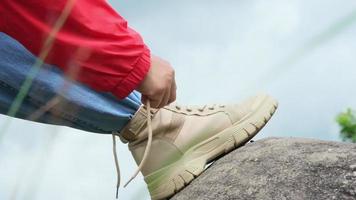 primo piano delle mani femminili che legano i lacci delle scarpe sullo stivale in una foresta di montagna. escursionista che si prepara per l'escursionismo. video