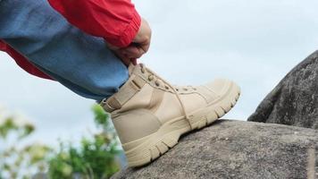 primer plano de manos femeninas atando cordones de zapatos en el arranque en un bosque de montaña. excursionista preparándose para el senderismo. video