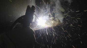 primer plano mano de soldador de metal que trabaja con una máquina de soldadura por arco para soldar acero en la fábrica con dispositivos de seguridad. saltan chispas y destellos. video