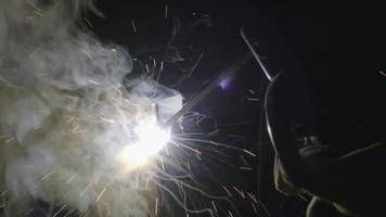 Close-up hand of Metal welder working with an arc welding machine to weld steel at the factory with safety devices. Sparks and flashes fly. video