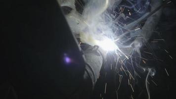 Close-up hand of Metal welder working with an arc welding machine to weld steel at the factory with safety devices. Sparks and flashes fly. video