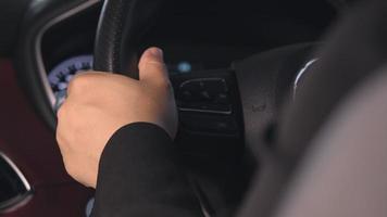 Close-up of the hand of a female driver in suit on the steering wheel of a car. The driver is turning the steering wheel in the car. Concept of transportation and technology
