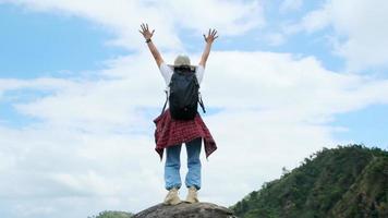 backpacken vrouwelijke wandelaar staat op de top van de berg met opgeheven armen en genieten van het uitzicht. reis en succes concept video