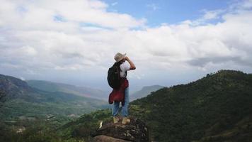 una excursionista mochilera se encuentra en la cima de la montaña y disfruta de la vista. concepto de viaje y éxito
