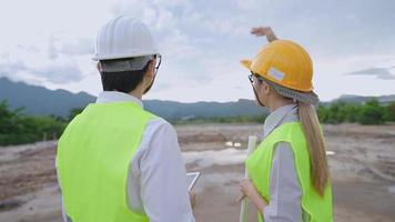 architecture de jeune ingénieur asiatique en uniforme de travail protégé de sécurité discutant d'un projet sur un chantier de construction en plein air, domaine de travail d'expertise spécialisée, innovation dans l'industrie de l'investissement immobilier video