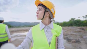 Young female engineer wear safety gears looking at architectural blueprints drawing paper, structure planner real estate worker, safety first, outdoor construction site, manufacture project employee video