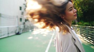 Portrait of attractive young cheerful female in summer scene, beautiful woman with long faded blonde hair turning around herself happily, sun flare illuminate, slow motion video of woman spinning