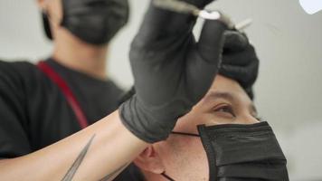 barbería masculina asiática, hombre con máscara negra se corta el pelo. oportunidad de trabajo peluquero. peine de agua, negocio de barbería durante el virus de la corona covid-19 reabrir el negocio después de la anticuarentena pandémica video