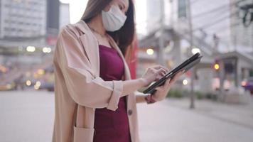 Working woman in formal clothing touching on tablet touch screen while stnading outside the office building, modern smart life surrounded by city urban structure, wireless technology for communication video