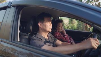 asiatische familie im auto, vater mittleren alters, der ein lenkrad auf dem fahrersitz steuert, wochenendaktivität, familienmitglied trifft sich, älteres paar auf der reise, lebensstil im ruhestand
