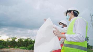 Asian Engineer architecture wear safety vest helmet discuss on working project at construction site, complex expertise working field, work gear blueprints paper, cooperating teamwork, option decision video