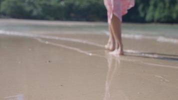 toma borrosa de una mujer descalza caminando por la playa de arena fina, disfruta de las olas del mar golpeando los pies, clima cálido y soleado, agua clara del océano, viaje refrescante, mar del sur de la India, andaman ocean island hopping video