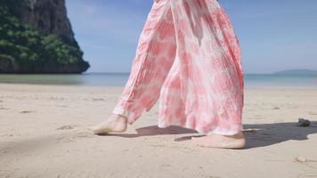piernas de mujer elegante caminando en la playa de la isla, pequeñas olas tranquilas. clima cálido y soleado, agua clara del océano, reserva de planes de paquetes de viaje, vacaciones de verano, vista lateral, horizonte marino y cielo video