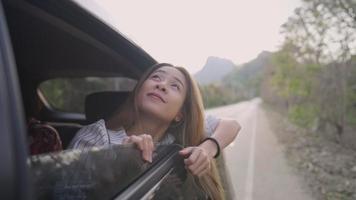 Blonde girl sticking out of car's window and enjoying trip through country road, Young woman extended her head out of moving auto with her long hair dropped outside of door's car, vacation summer vibe video