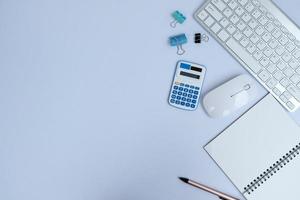 Blank notebook, a pen, and eyeglasses are on top of a white office desk table. Flat lay, top view. White designer office desk table with laptop, smartphone and supplies photo