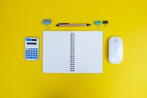 Blank notebook, a pen, and eyeglasses are on top of a white office desk table. Flat lay, top view. White designer office desk table with laptop, smartphone and supplies photo