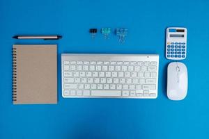 Blank notebook is in the middle of office desktable with pen and office supplies. Top view, flat lay. photo
