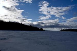 a winter storm approaches over a frozen lake