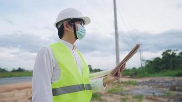 An electrical worker engineer working with digital tablet while standing on rural rough road, energy business technology industry concept, professional senior worker studying reading on blueprint video