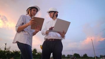 Asian Engineer architecture investor wear safety protective hardhat survey at outdoor construction site debriefing work during sunset, specialist expert working field, Real Estate industry innovation video