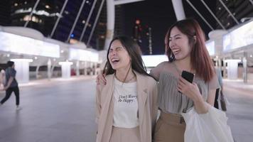 Attractive asian female cheerful friends having a walk together on a city walking bridge in night time, teenage enjoying their youth and free time, female stylish outfits or charming appearance video