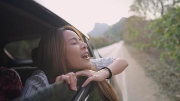 Young attractive blonde daughter enjoying a good feeling of breath in fresh air while on family travelling outside of city, portrait of teenage extend her head out of opened car's window, healthy Life video