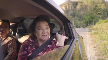 glad fashionabel pensionerad kvinna som viftar med handen ut genom bilfönstret, två bra friska äldre kvinnor njuter av utsikten från bilresans fönster, frihet och lycka i pensionsåldern video