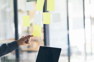 Business people meeting at office and use post it notes to share idea. Brainstorming concept. Sticky note on glass wall. photo