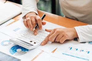 Close up hand of businessman or accountant hand holding pen working on calculator to calculate business data, accountancy document and laptop computer at office, business concept. photo