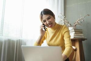 Asian woman in casual clothes is happy and cheerful while communicating with her smartphone and working in a coffee shop. photo