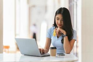 Online Banking Concept. Portrait Of Happy Young Asian Woman With Laptop And Credit Card Sitting in cafe, Smiling Asian Women Enjoying Making Payments From Home. photo