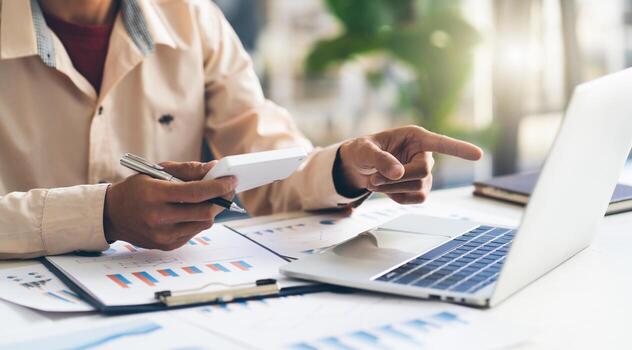 Asian business man working and data analysis with computer laptop in office, business financial and investment concept. photo