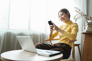 Asian woman in casual clothes is happy and cheerful while communicating with her smartphone and working in a coffee shop. photo