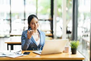 Asian female talking about sale report in video conference. Asian team using laptop and tablet online meeting in video call.Working from home remotely. photo