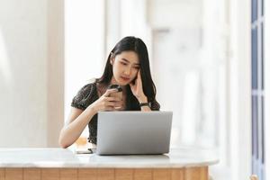 retrato de una joven asiática que trabaja en una laptop y un informe financiero en la oficina. foto