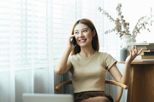 Asian woman in casual clothes is happy and cheerful while communicating with her smartphone and working in a coffee shop. photo