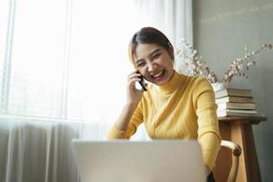 Asian woman in casual clothes is happy and cheerful while communicating with her smartphone and working in a coffee shop. photo