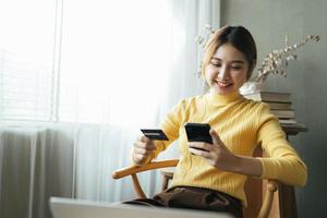 Asian woman in casual clothes is happy and cheerful while communicating with her smartphone and working in a coffee shop. photo