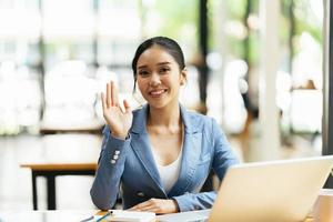 Asian female talking about sale report in video conference. Asian team using laptop and tablet online meeting in video call.Working from home remotely. photo