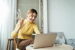 Asian woman having video call on her computer at home. Smiling girl studying online with teacher. photo