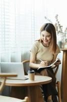 Portrait of Asian young female working on laptop and financial report at office. photo