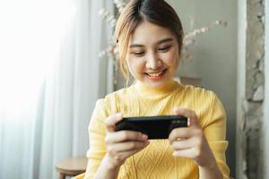 mujer asiática emocionada mientras juega juegos móviles, lee buenas noticias mientras navega por el mundo de Internet. foto