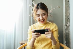 mujer asiática emocionada mientras juega juegos móviles, lee buenas noticias mientras navega por el mundo de Internet. foto
