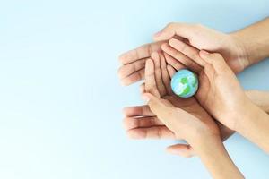 Happy earth day - Top view of two hands hold earth on blue background photo