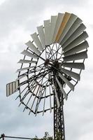 Vertical shot of an antique windmill turbine against the cloudy sky photo