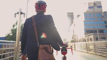 Geschäftsmann in formeller Kleidung mit Helm auf dem Kopf, der sein Fahrrad in der Hauptverkehrszeit durch die Überführung über den Stau schiebt. junge Berufstätige genießen den Blick auf die Straße in der Stadt, abseits vom Verkehr video
